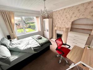 a bedroom with a bed and a red chair at Stonehouse Cottage Near QE & UOB in Birmingham