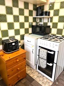 a kitchen with a white stove and a microwave at Stonehouse Cottage Near QE & UOB in Birmingham