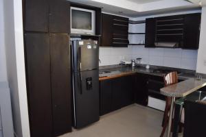 a kitchen with black cabinets and a stainless steel refrigerator at Penthouse Rodadero Norte in Gaira