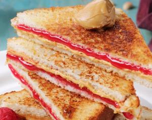 two halves of a sandwich on a plate with strawberries at Deluxe Residency Nr- Mumbai International Airport in Mumbai