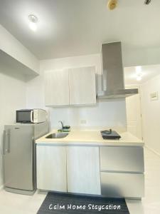 a white kitchen with a sink and a refrigerator at Condo in Azure Urban Resort Residences-Paranaque City in Manila