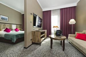 a hotel room with a bed and a couch and a tv at Hotel Fado Spa & Restaurant in Świdnica