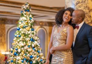 a man and a woman standing in front of a christmas tree at Fairmont San Francisco in San Francisco