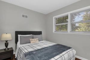 ein weißes Schlafzimmer mit einem Bett und zwei Fenstern in der Unterkunft Prime Location, Cozy & Spacious home in Schaumburg in Schaumburg