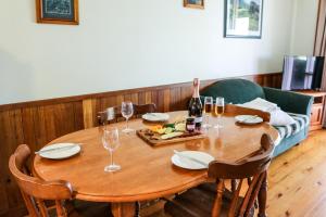 a wooden table with glasses and a bottle of wine at Carriageway Retreat - Unique Red Rattler Carriages and Units in Brookfield