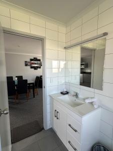 a bathroom with a sink and a mirror and a dining room at Eastland Pacific Motor Lodge in Opotiki