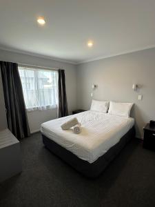 a bedroom with a large bed with white sheets and a window at Eastland Pacific Motor Lodge in Opotiki