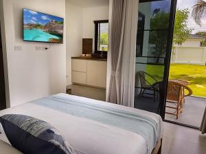 - une chambre avec un lit et une télévision murale dans l'établissement Bungalow Khao Lak, à Khao Lak