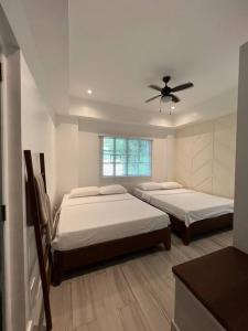 1 dormitorio con 2 camas y ventilador de techo en Beachfront Reunions @ Canyon Cove en Nasugbu