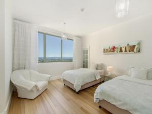 a white bedroom with two beds and a chair at Style and Amazing Views-Sub Penthouse in Gold Coast +11 photos