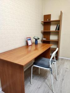 escritorio de madera con silla y estante para libros en Central Oak Park Apartment, en Bishkek