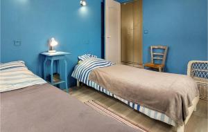 - 2 lits dans une chambre aux murs bleus dans l'établissement Cozy Home In Saint-georges-de-didon With Kitchen, à Saint-Georges-de-Didonne