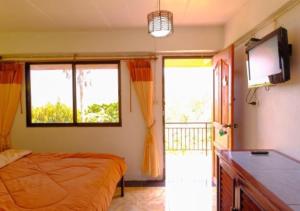 ein Schlafzimmer mit einem Bett und einem Fernseher und Fenstern in der Unterkunft Ban Rabiengfah Resort in Ban Seng Choi
