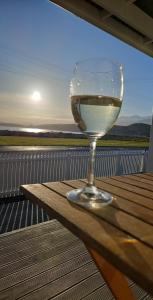 a glass of wine sitting on a wooden table at K'orca Cottage by the Sea in Kaikoura