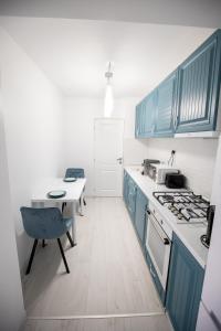 uma cozinha com armários azuis, uma mesa e um fogão em Alpasio Rentals 2 em Galaţi