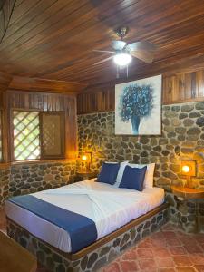 1 dormitorio con 1 cama con pared de piedra en Bungalows Malú, en Cahuita