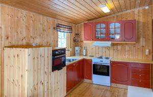 una cucina con pareti in legno e armadi rossi di 3 Bedroom Nice Home In Bjorli a Bjorli