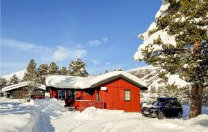 a red cabin in the snow with a car in front at 3 Bedroom Nice Home In Bjorli in Bjorli