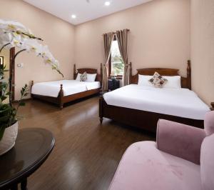 two beds in a room with a table and a couch at Four Spring Villas & Golfs Da Lat in Da Lat