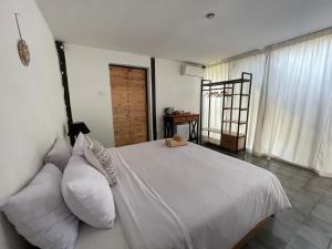 a bedroom with a white bed with a teddy bear on it at BB Garden Resort in Canggu