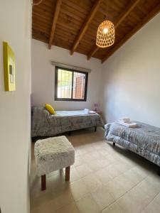 a room with two beds and a chair and a chandelier at Las Balda, tu casita en Viedma in Viedma
