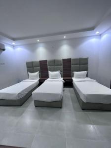 Habitación con 3 camas y luces. en ليالي الراحة للوحدات السكنية, en Taif