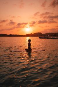 una persona sentada en una tabla de surf de remo en el agua en SEA HILLS Kuta Lombok, en Kuta Lombok