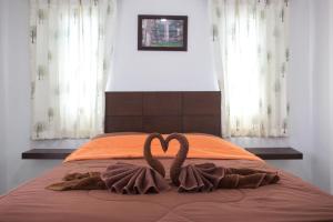 Ban Thung Chao的住宿－Treeside Guest House Resort，两个天鹅在床上形成心