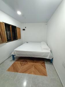 Habitación blanca con cama y suelo de madera. en Urantia Beach Hostel & Camping en San Onofre