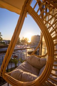 a wicker chair on a balcony with the sunset at AIOLOS GLYFADA luxury sea view suite 5 in Athens