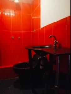 La salle de bains rouge est pourvue de toilettes et d'un lavabo. dans l'établissement Departamento Amoblado, à Huaraz