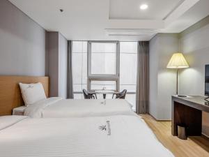 a hotel room with two beds and a table at Haeundae Seacloud Hotel Residence in Busan