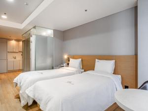 two beds in a room with white sheets at Haeundae Seacloud Hotel Residence in Busan