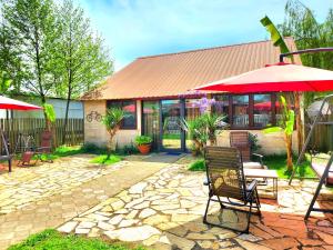 un patio avec des chaises et un parasol et un bâtiment dans l'établissement House & Yard Sesil XL 90m to beach, à Ureki