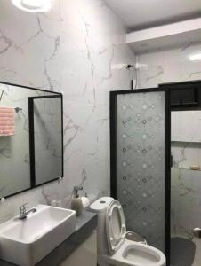 La salle de bains est pourvue d'un lavabo, de toilettes et d'un miroir. dans l'établissement PMPJ Staycation, à Lipa