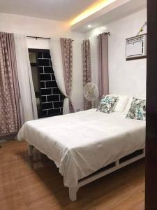 a bedroom with a white bed and a window at PMPJ Staycation in Lipa