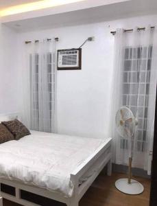 a white bedroom with a bed and a fan at PMPJ Staycation in Lipa