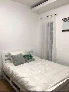 a white bed with two pillows on it in a bedroom at PMPJ Staycation in Lipa +10 photos