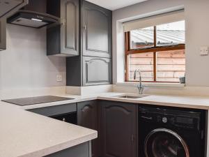 a kitchen with a sink and a washing machine at Voelas Cottage Annexe in Llong