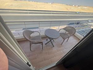 três cadeiras e uma mesa numa varanda com piscina em Maison de repos em New cairo