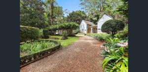 a garden with a house and some bushes and flowers at The Gamekeepers Spa Cottage in Tamborine Mountain in Mount Tamborine