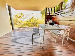 a white table and chairs on a porch with a bench at Cosy Apartment at Sebel Twin Waters Resort w Private Garden - 2 Mins Walk to Beach & River in Mudjimba