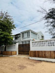 une maison blanche avec une clôture en bois devant elle dans l'établissement Casa Cinza, à Ponta do Ouro