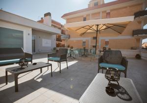 patio z krzesłami, stołami i parasolem w obiekcie Castrichella Boutique Hotel Rome Airport w mieście Fiumicino