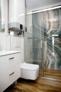 ein weißes Bad mit einem WC und einer Dusche in der Unterkunft Ahoy Relax Apartmán Ocean in Nesvady