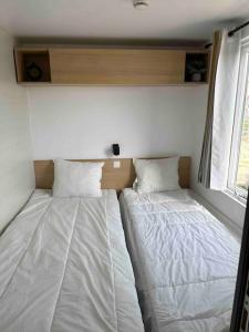 two beds sitting in a small room with a window at Mariseltinyhouse in Mărişel +26 photos