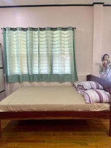 a bed in a room with a green window at Maria Kulafu Kubo House 1 BIG BEDROOM with Wifi in Masbate