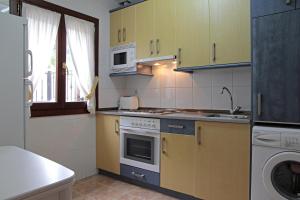 a kitchen with yellow cabinets and a stove top oven at Apartamentos Irati Olaldea in Oroz-Betelu