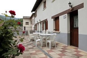 un patio con mesa, sillas y rosas en Apartamentos Irati Olaldea, en Oroz-Betelu