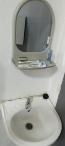 ein Waschbecken mit einem Spiegel an der Wand in der Unterkunft JSW Inn in Gelugor